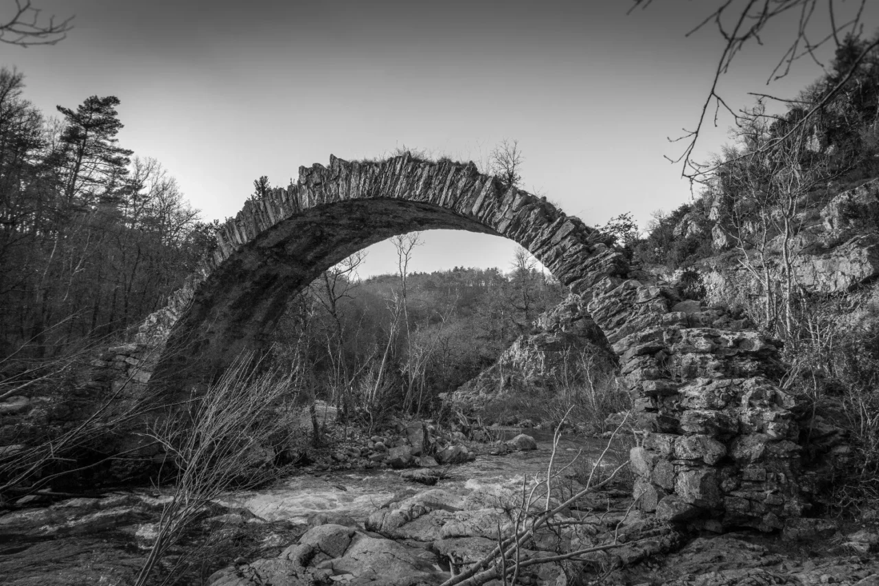 Pont romain en lauzes à une arche au-dessus d'une rivière ardéchoise